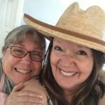 Paoloa Jo wearing a hat and smiling with smiling quilty friend