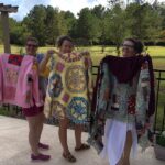 Paola Jo and two ladies at a Workshop holding up their Quilt Coat creations.